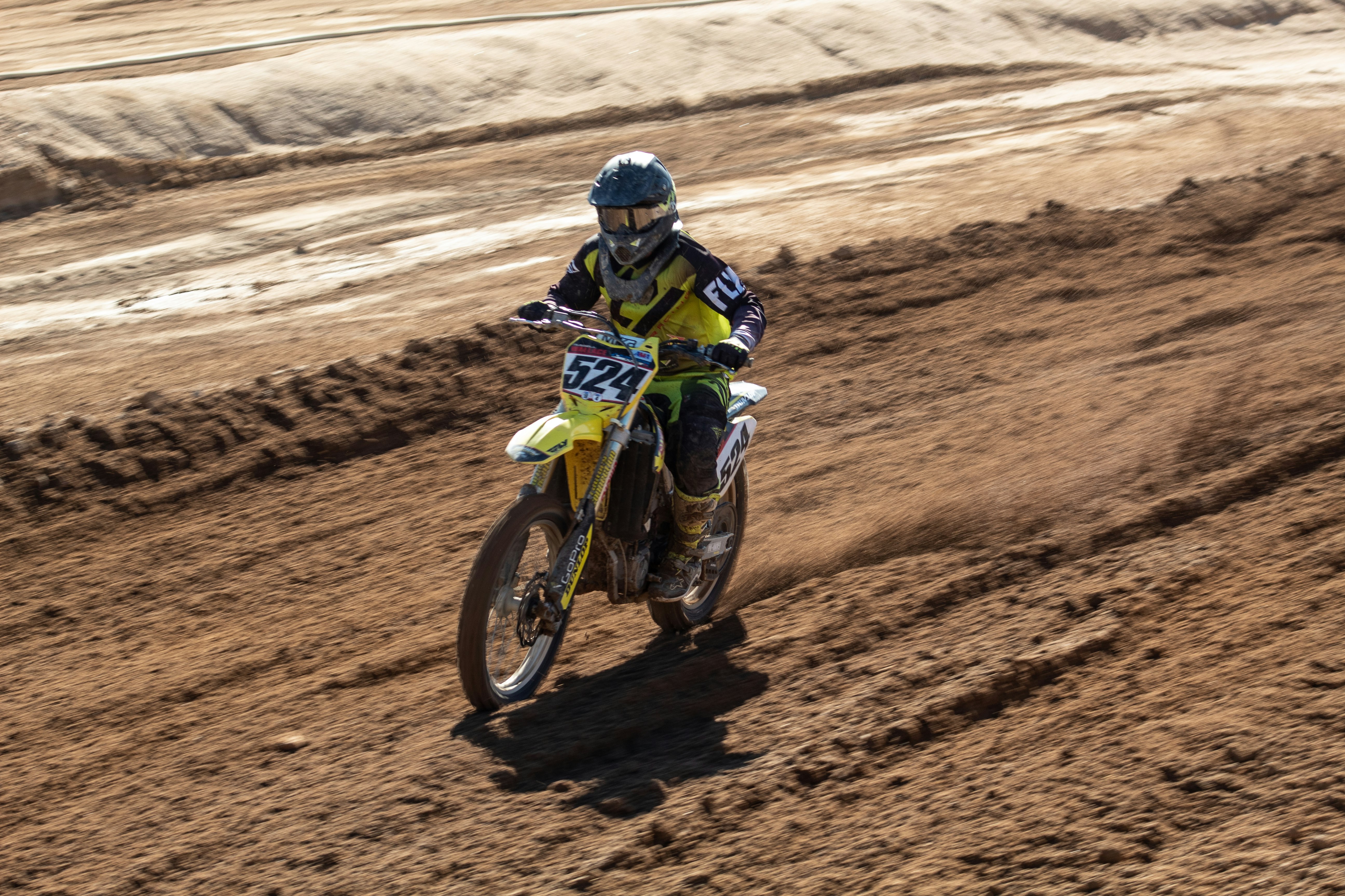 man riding motocross dirt bike on brown sand during daytime